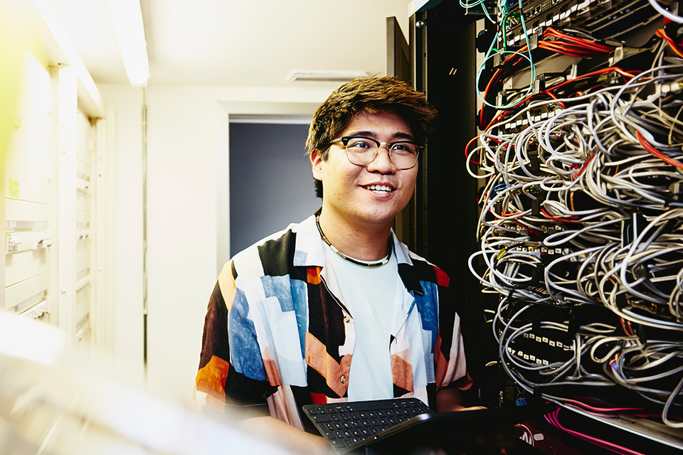 Smiling man holding an tablet standing in a servers room.