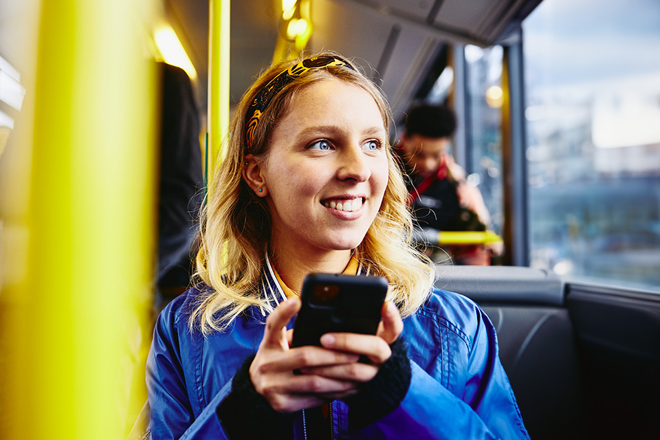 woman in bus looking out the window on her mobile phone