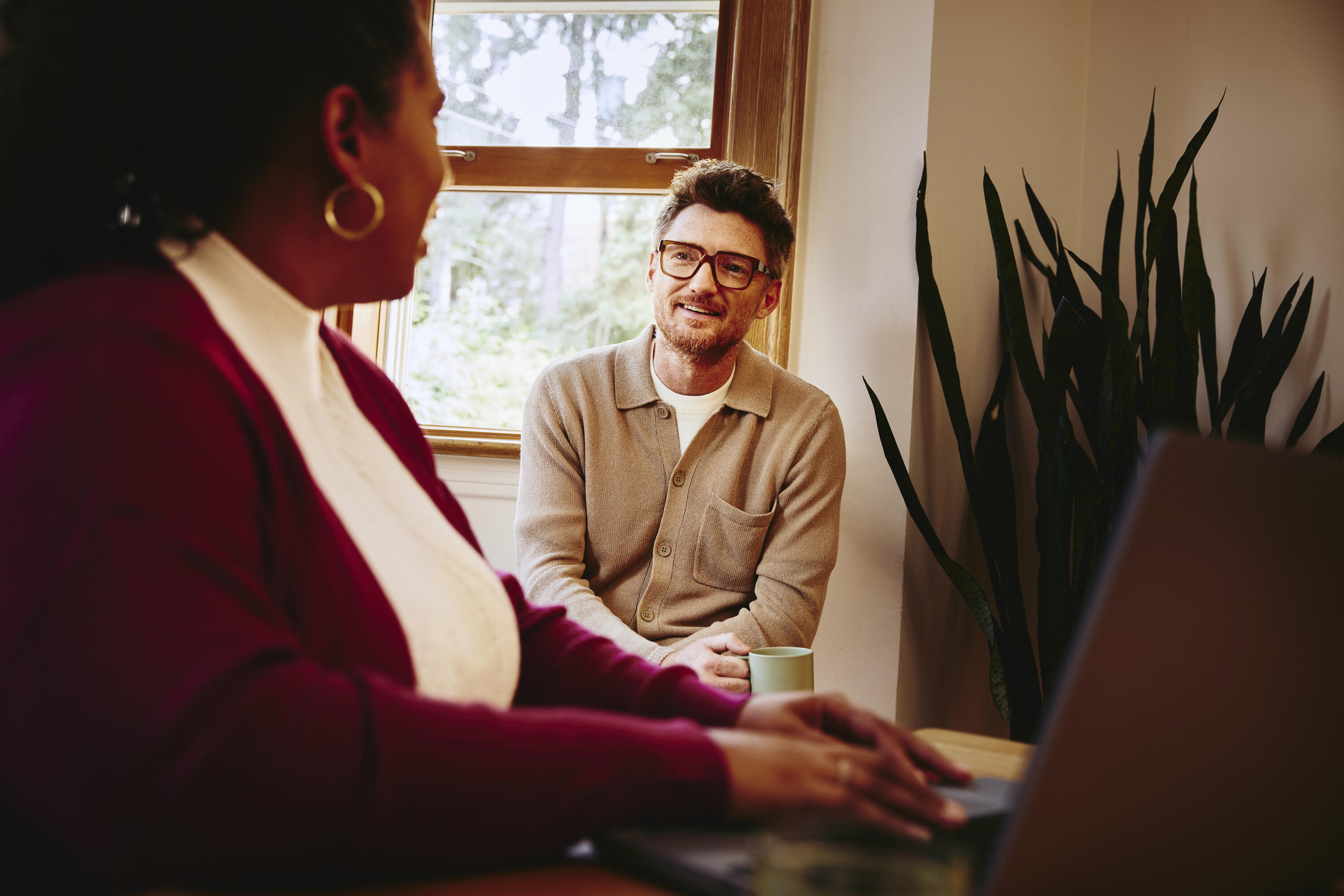 Female behind her laptop talking to male next to her at home
