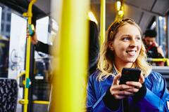 woman smiling on the bus using her phone