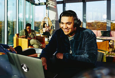 male sitting in a cafe working on his laptop smiling