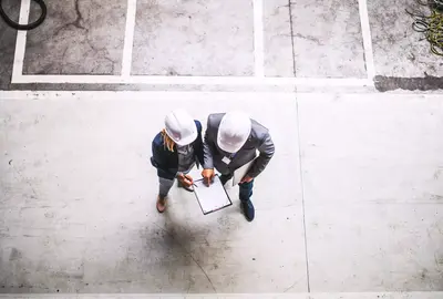 A top view of an industrial man and woman engineer with clipboard in a factory. 