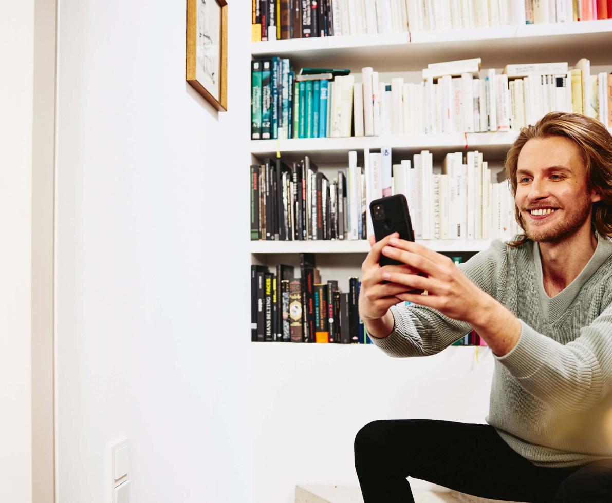 young male sitting taking selfie on phone