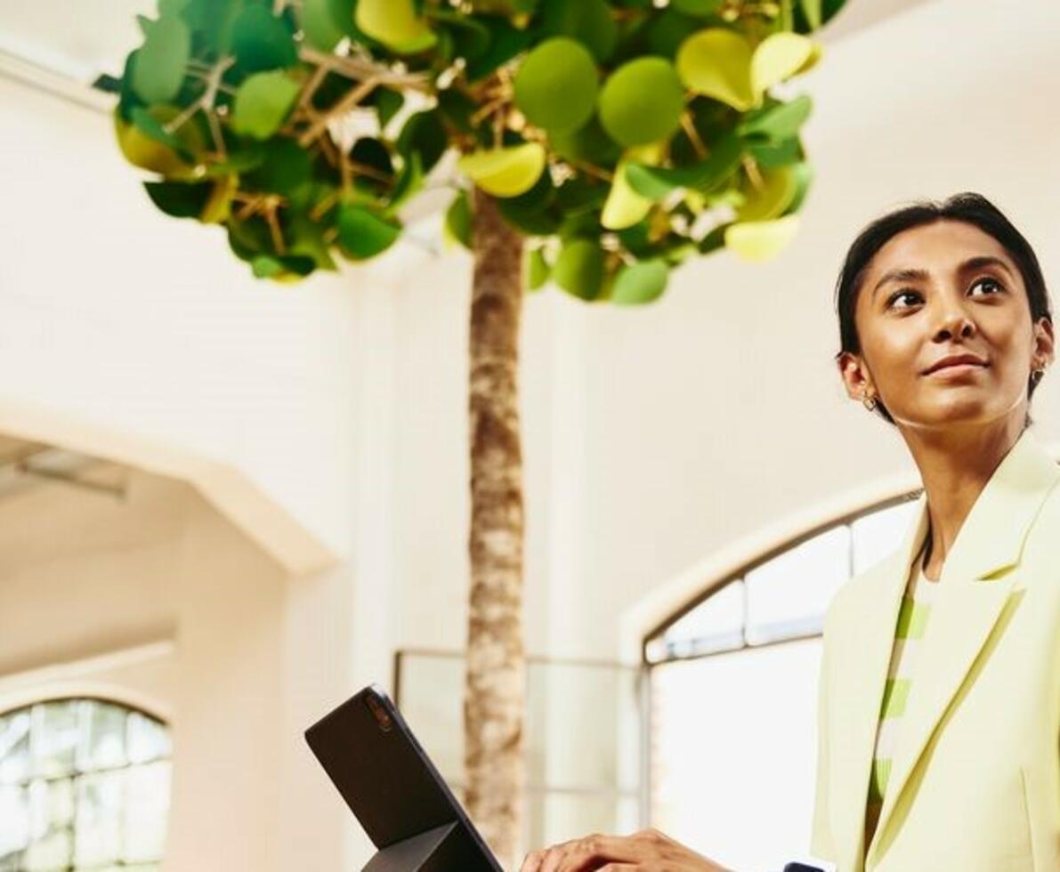 indian woman sitting at a high table working on a tablet