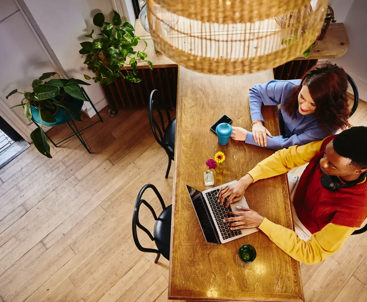 man and woman sitting at a table looking at their laptop