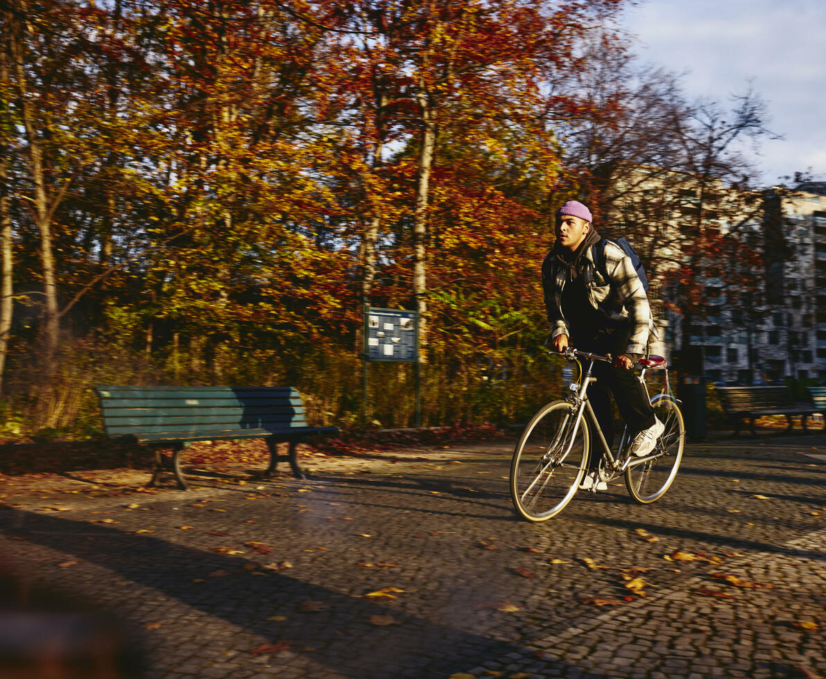 Cycling male, autumn trees and office buildings on the background.
