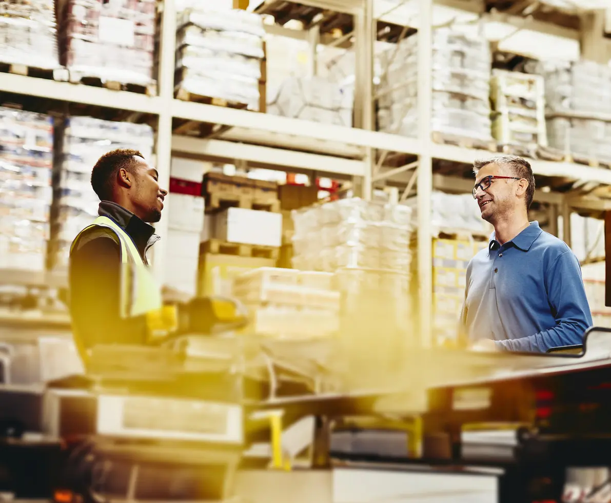 Two male working/having a conversation in a warehouse
