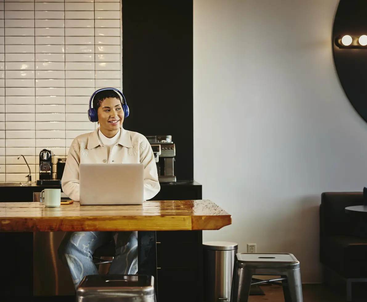 Man with headphones working on laptop at a table in a cafe