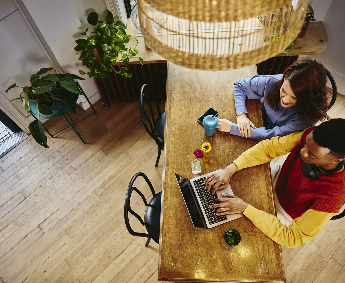 Bird view of a female and male working on a laptop at a table