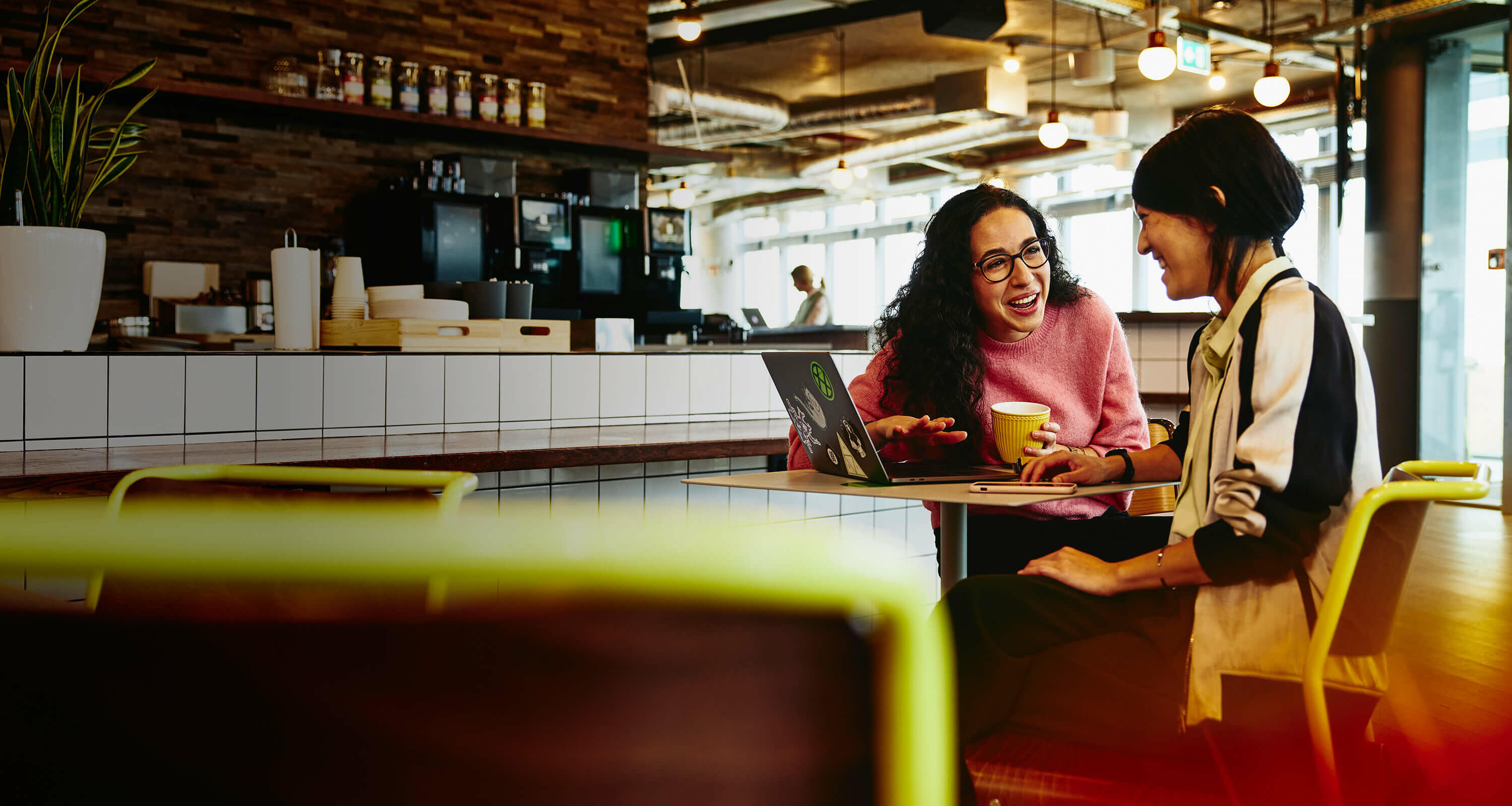 two women sitting in a restaurant with a laptop