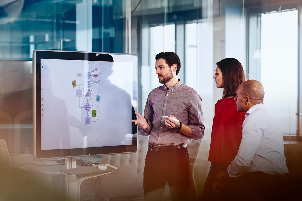 Team working on a Google Jamboard in an office. 
